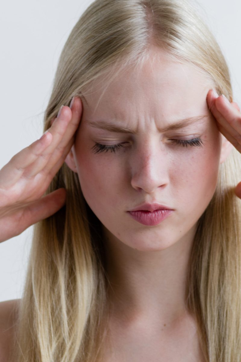 Headache woman portrait. Girl with pain head and neck  over gray wall. Studio shot.